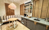 A kitchenette area in a beachfront one-bedroom villa suite accommodation features a stocked bar and coffee station, as well as a kitchen table with banquette seating.