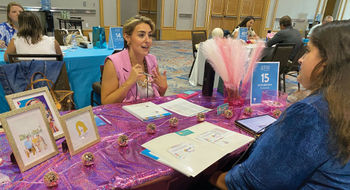 Katie Brown, an independent contractor with Travelmation in Marietta, Ga., meets with a supplier at her Dolly Parton-themed table hoping the colorful decor will make her easier for suppliers to remember later on.