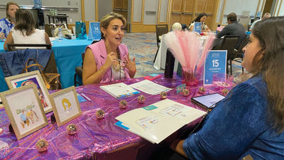 Katie Brown, an independent contractor with Travelmation in Marietta, Ga., meets with a supplier at her Dolly Parton-themed table hoping the colorful decor will make her easier for suppliers to remember later on.