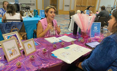 Katie Brown, an independent contractor with Travelmation in Marietta, Ga., meets with a supplier at her Dolly Parton-themed table hoping the colorful decor will make her easier for suppliers to remember later on.