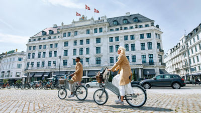 Visitors bike past D'Angleterre hotel in Copenhagen.