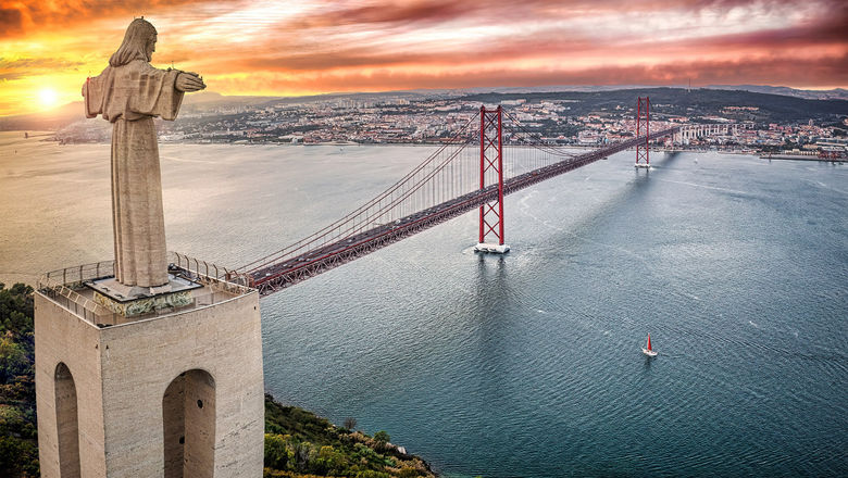 The Cristo Rei statue overlooking Lisbon from 25 Abril Bridge in Almada, Portugal.